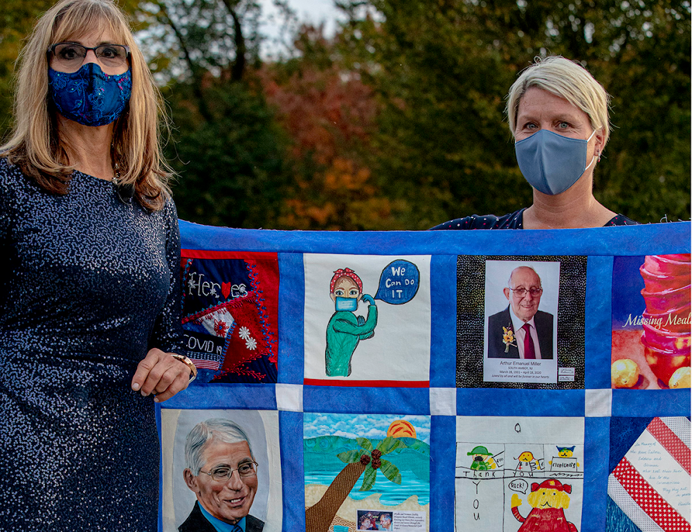 Diane Canney, founder of the COVID-19 HOPE Quilt Project, and Betsy Scotto-Lavino, Director of Research and Education for Artistic Fuel, pose with a quilt